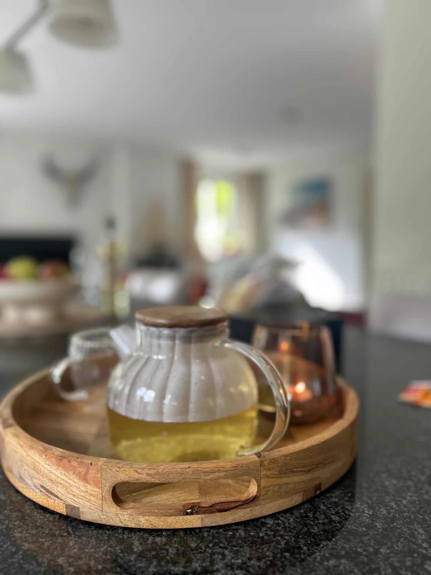 Glazen theepot met thee op een houten dienblad, in het warme interieur van Livin'Room